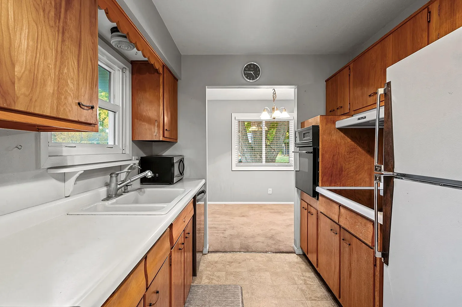 Galley kitchen with wood cabinetry and a window over the sink